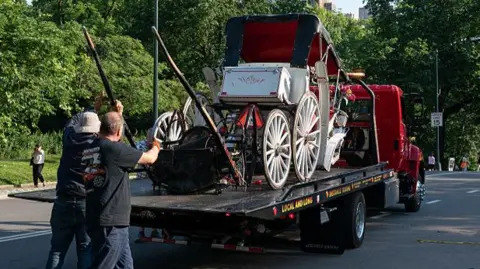 A damaged horse carriage is pictured being removed from Central Park on a truck